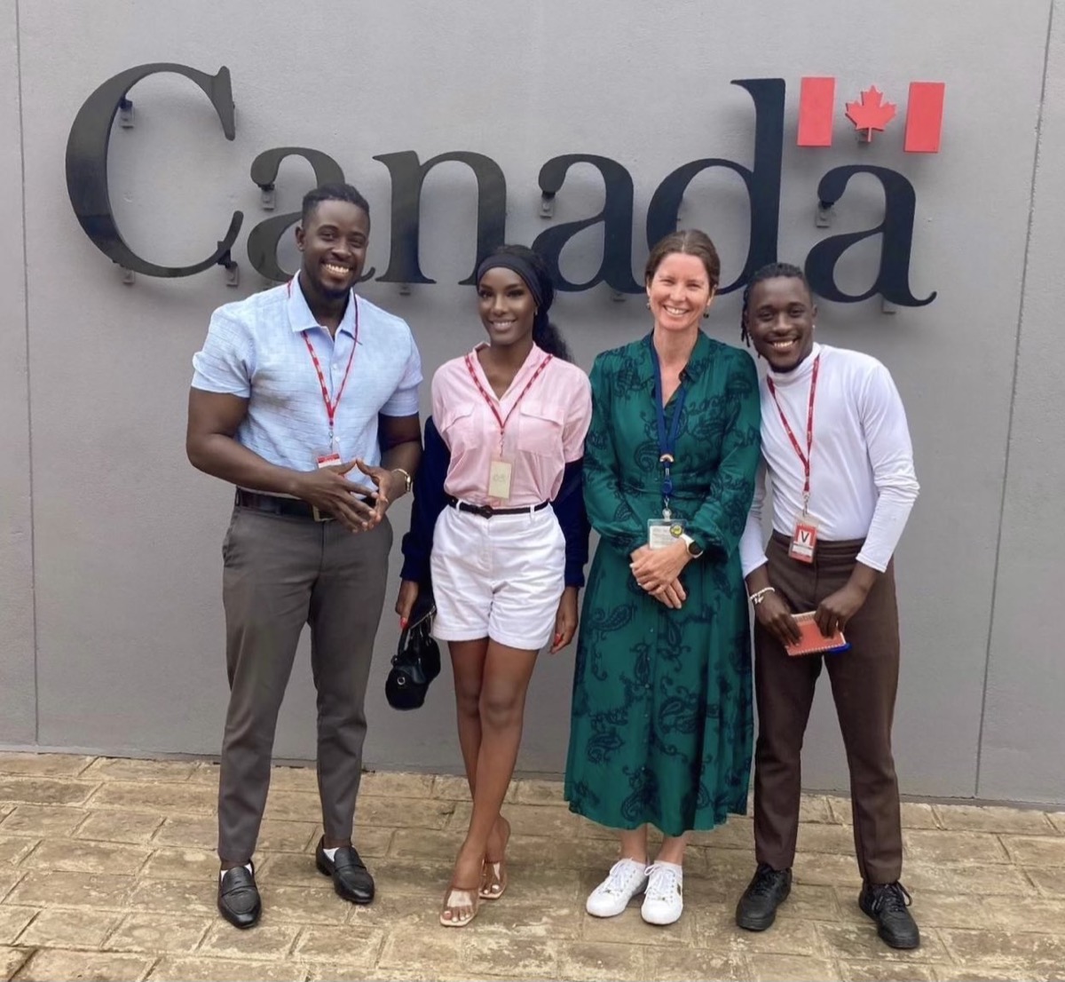 Four people standing in front of the Canada sign